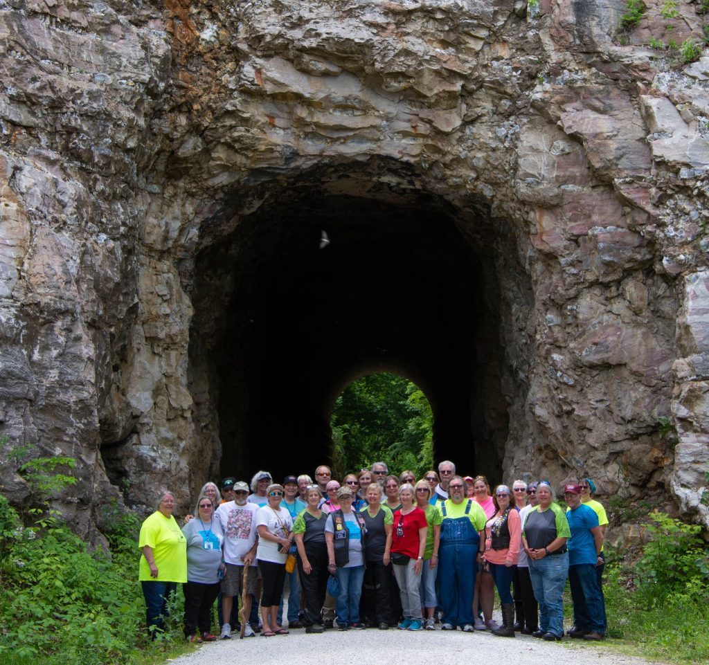Large group standing in front of a rock tunnel