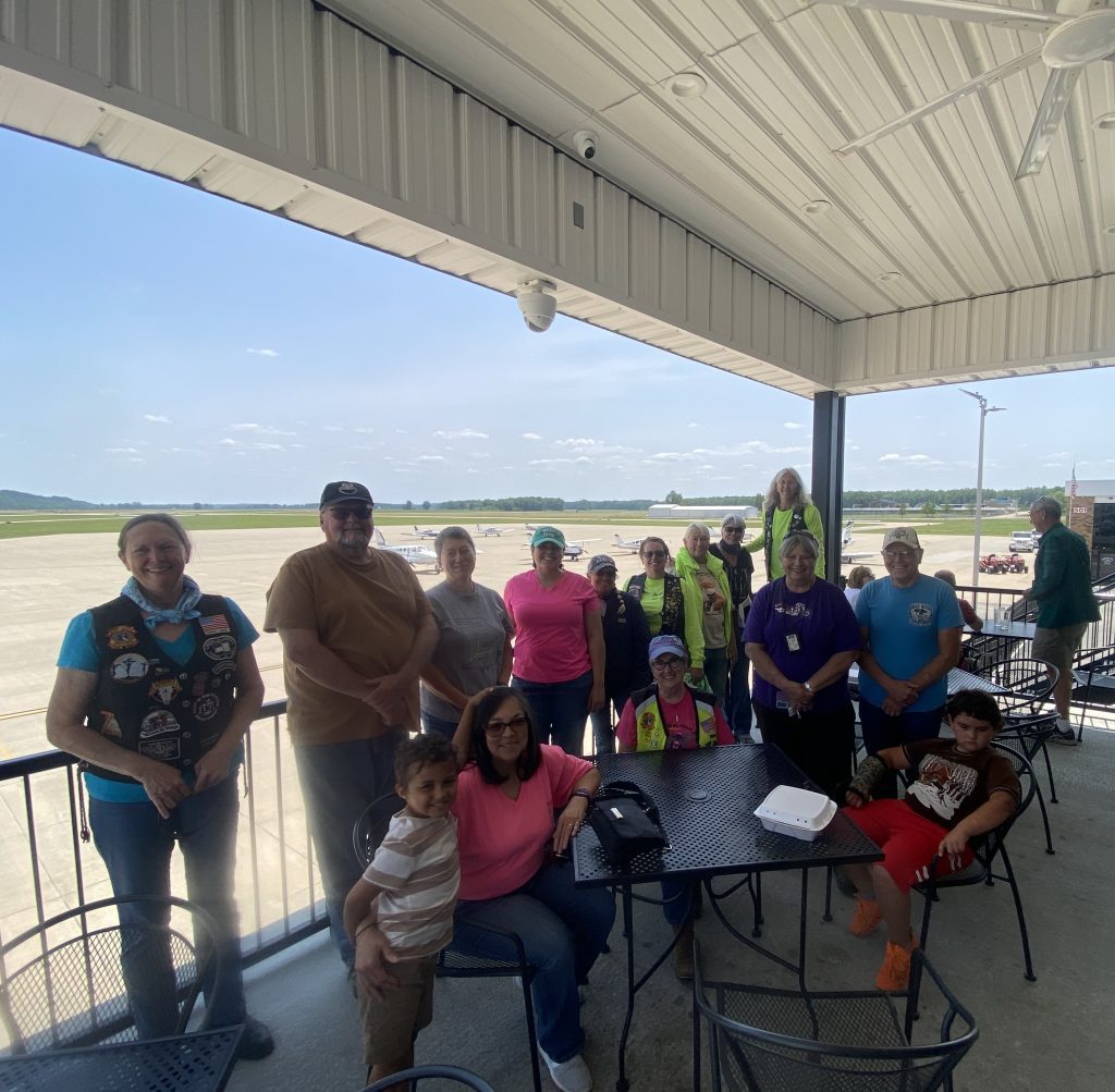 Riders gathered on a covered patio beside an airfield